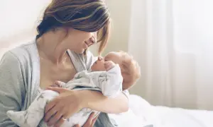 Mutter hält ihr Neugeborenes liebevoll im Arm. Ein Moment purer Zuneigung, eine stille Empfehlung für die innige Bindung zwischen Mutter und Kind.