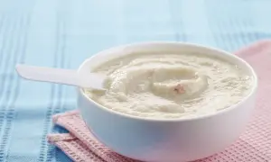 Schüssel mit cremigem Milch-Getreide-Brei, perfekt für ein einfaches und nahrhaftes Frühstück. Ein weißer Löffel liegt darin.