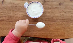 Kleiner Löffel mit Joghurt für ein Baby. Wann ist Joghurt für Babys geeignet?