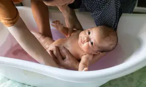 Ein Baby wird in einer Babybadewanne gebadet. Die Eltern prüfen die **Badetemperatur Baby**, damit es sich wohlfühlt.
