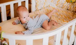 Baby liegt auf dem Bauch, der Schnuller im Mund. Es dreht sich noch nicht, aber die Beine sind schon aktiv.