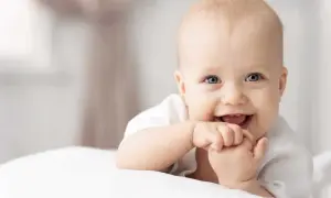 Ein lächelndes Baby mit blauen Augen, das auf einem weißen Kissen liegt. Tolle 4. sprung baby erfahrungen!