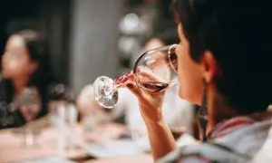Frau trinkt Rotwein. Die Frage "darf man beim stillen Alkohol trinken?" beschäftigt viele.