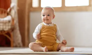 Ein fröhliches Baby sitzt auf dem Teppich. Die meisten Babys können ab dem 6. Monat sitzen.