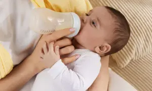 Baby trinkt aus Flasche, vielleicht wegen Wachstumsschub. Es spuckt danach mehr, aber das ist normal.