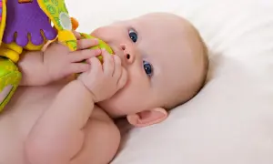 Baby mit blauen Augen erkundet sein buntes Spielzeug. Ein typischer Moment im 19 wochen schub, voller Entdeckungen.