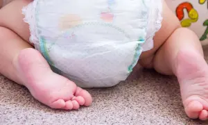 Babyfüße neben einer Windel. Bei Windeldermatitis hilft schnell eine gute Pflege.