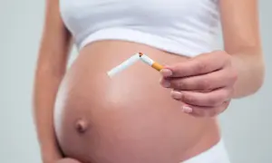 Schwanger, die eine zerbrochene Zigarette hält. Nikotin in Muttermilch schadet dem Baby.