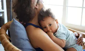 Ein Baby kuschelt sich an seine Mutter. Es ist 37 wochen schub, und es sucht Trost und Sicherheit in ihren Armen.