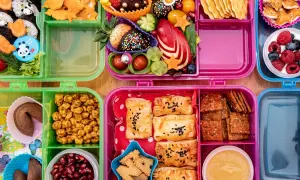 Bunte Bento-Boxen voller leckerer Snacks für die Autofahrt: Sushi, Obst, Kekse und Gebäck.