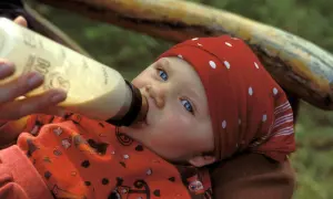 Ein Baby mit blauen Augen trinkt aus einer Flasche. Die Frage "wieviel sollten Kleinkinder trinken" beschäftigt viele Eltern.