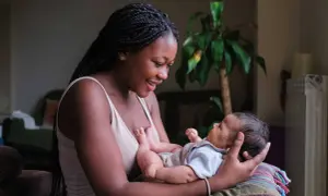 Eine junge Mutter lächelt ihr Baby an, das sie im Arm hält. Sie strahlt pure Energie in der Stillzeit aus.