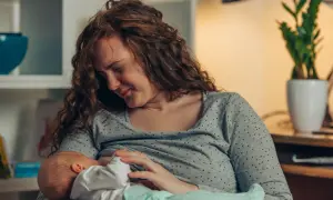 Mutter mit rissigen Brustwarzen stillt ihr Baby liebevoll, trotz des Schmerzes.
