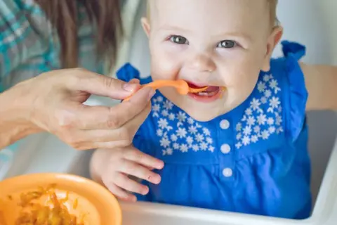 Ein Baby isst Brei. Die Frage, warum Beikost erst ab 6 Monaten empfohlen wird, wird hier bildlich beantwortet: Geduld ist wichtig für die Entwicklung.
