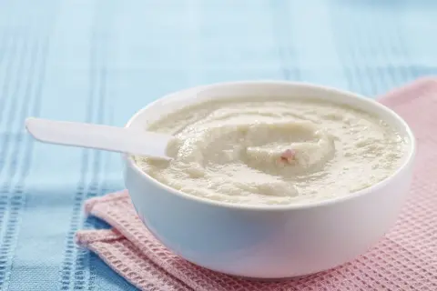 Schüssel mit cremigem Milch-Getreide-Brei, perfekt für ein einfaches und nahrhaftes Frühstück. Ein weißer Löffel liegt darin.