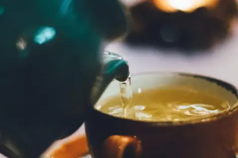 Ein warmer Tee wird in eine Tasse gegossen. Perfekt für die Tee Stillzeit.