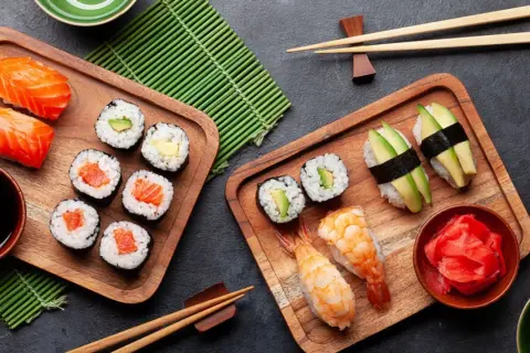 Sushi-Stillzeit: Frischer Lachs, Avocado und Garnelen auf Holzbrettern, bereit zum Genießen. Ein Fest für die Sinne.