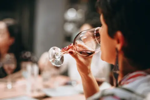 Frau trinkt Rotwein. Die Frage "darf man beim stillen Alkohol trinken?" beschäftigt viele.
