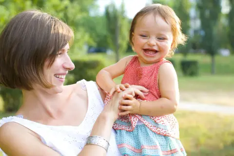 Mutter hält ihr lachendes Baby, das wie ein **baby sprung** vor Freude aussieht.