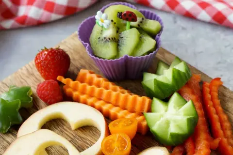 Buntes Obst und Gemüse für ein Baby von 1 Jahr: Erdbeeren, Kiwi, Karotten, Gurken, Paprika, Apfelherzen.
