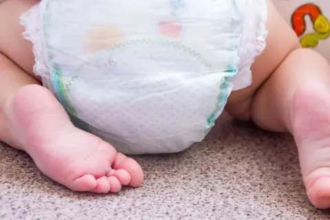 Babyfüße neben einer Windel. Bei Windeldermatitis hilft schnell eine gute Pflege.
