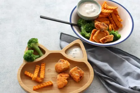Fischstäbchen mit Brokkoli und Süßkartoffel-Pommes auf einem Katzen-Teller. Ab wann Fisch Baby essen darf, ist eine Frage für Eltern.