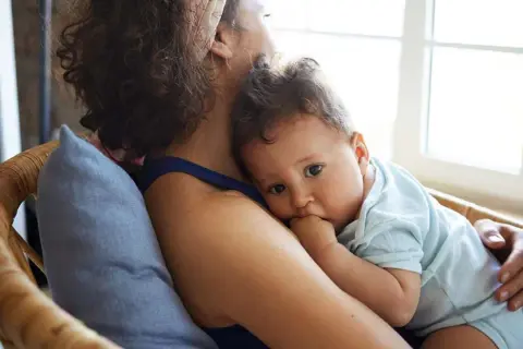 Ein Baby kuschelt sich an seine Mutter. Es ist 37 wochen schub, und es sucht Trost und Sicherheit in ihren Armen.