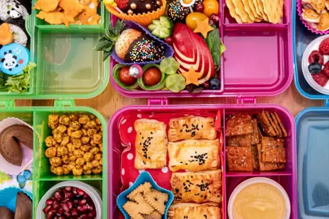 Bunte Bento-Boxen voller leckerer Snacks für die Autofahrt: Sushi, Obst, Kekse und Gebäck.