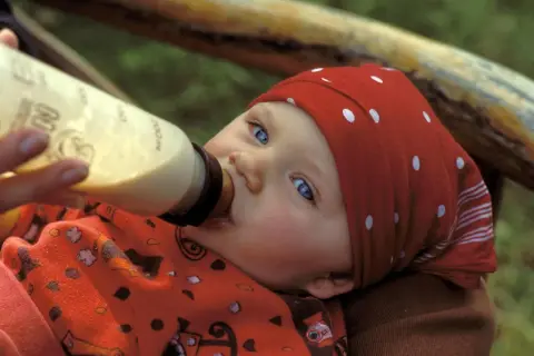 Ein Baby mit blauen Augen trinkt aus einer Flasche. Die Frage "wieviel sollten Kleinkinder trinken" beschäftigt viele Eltern.
