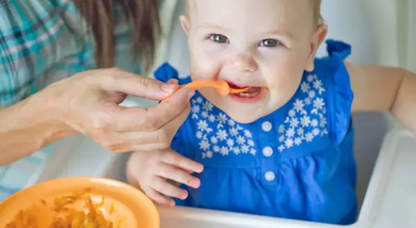 Ein Baby isst Brei. Die Frage, warum Beikost erst ab 6 Monaten empfohlen wird, wird hier bildlich beantwortet: Geduld ist wichtig für die Entwicklung.