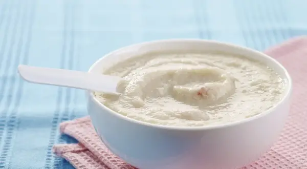 Schüssel mit cremigem Milch-Getreide-Brei, perfekt für ein einfaches und nahrhaftes Frühstück. Ein weißer Löffel liegt darin.