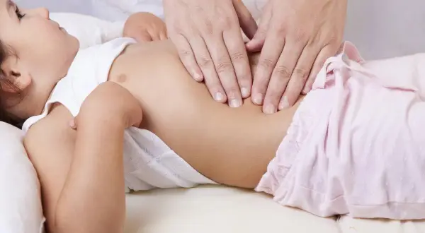 Arzt tastet Bauch eines Kindes ab, um Blinddarm Symptome bei Kindern zu erkennen.
