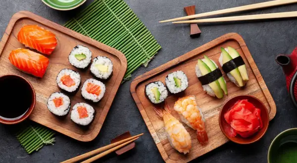 Sushi-Stillzeit: Frischer Lachs, Avocado und Garnelen auf Holzbrettern, bereit zum Genießen. Ein Fest für die Sinne.