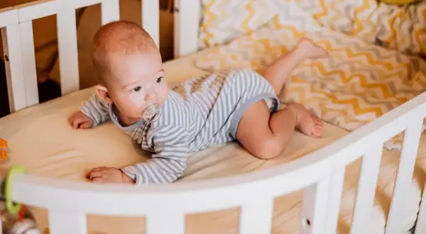Baby liegt auf dem Bauch, der Schnuller im Mund. Es dreht sich noch nicht, aber die Beine sind schon aktiv.