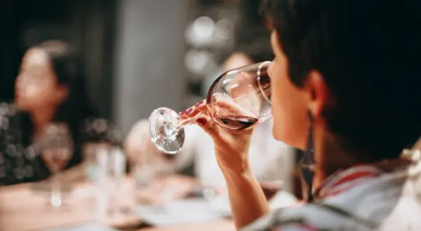 Frau trinkt Rotwein. Die Frage "darf man beim stillen Alkohol trinken?" beschäftigt viele.