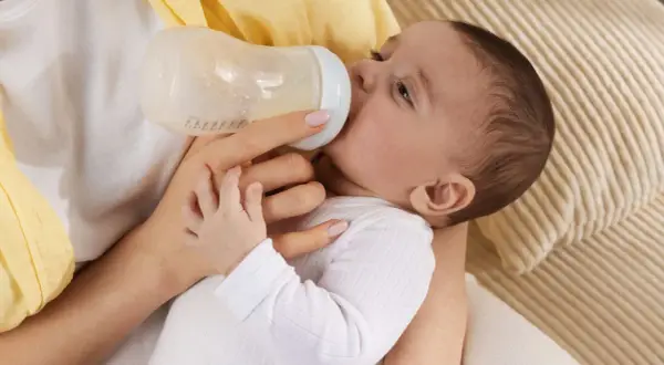 Baby trinkt aus Flasche, vielleicht wegen Wachstumsschub. Es spuckt danach mehr, aber das ist normal.