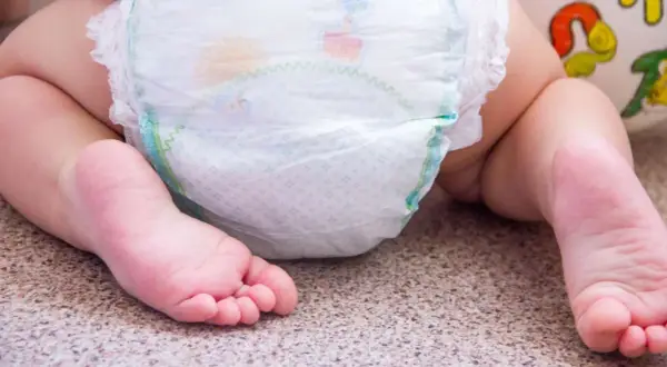 Babyfüße neben einer Windel. Bei Windeldermatitis hilft schnell eine gute Pflege.