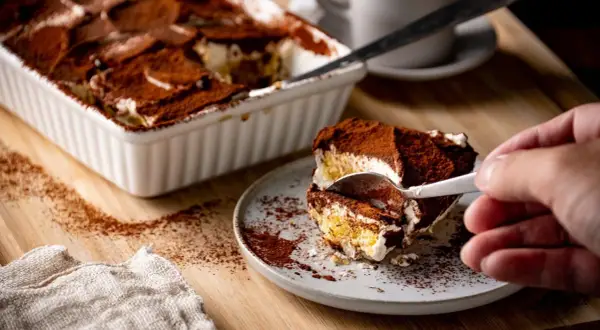 Ein Stück Tiramisu wird mit einer Gabel aus einer Auflaufform genommen. Perfekt für die Stillzeit!