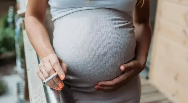 Schwanger, mit Zigarette in der Hand. Ein Moment der Ruhe, der jedoch Risiken birgt, besonders in der Stillzeit.