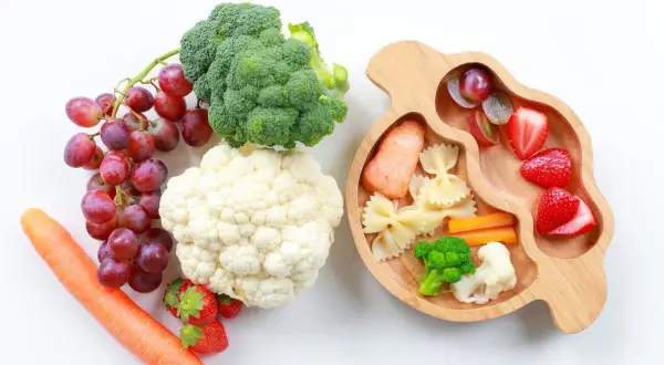 Baby led weaning rezepte: Lachs, Nudeln, Gemüse und Obst auf einem Holztablett.