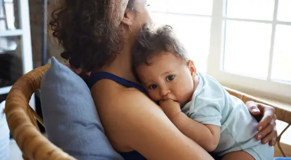 Ein Baby kuschelt sich an seine Mutter. Es ist 37 wochen schub, und es sucht Trost und Sicherheit in ihren Armen.