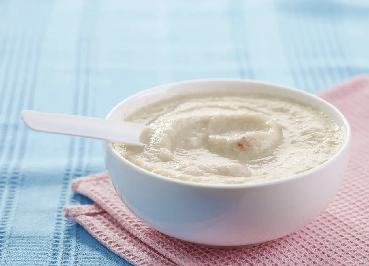 Schüssel mit cremigem Milch-Getreide-Brei, perfekt für ein einfaches und nahrhaftes Frühstück. Ein weißer Löffel liegt darin.