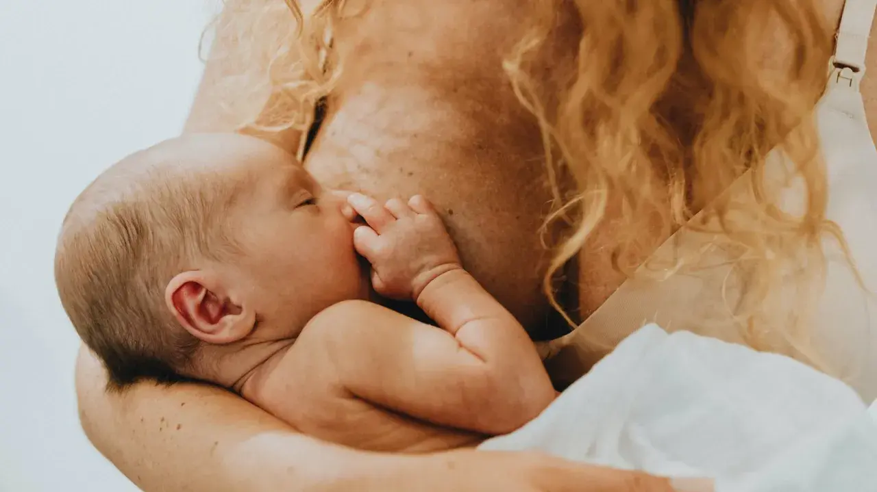 Ein Baby schreit beim Stillen, die Mutter hält es liebevoll.