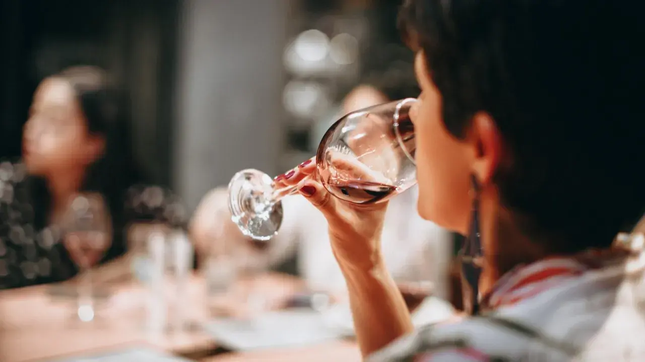 Frau trinkt Rotwein. Die Frage "darf man beim stillen Alkohol trinken?" beschäftigt viele.