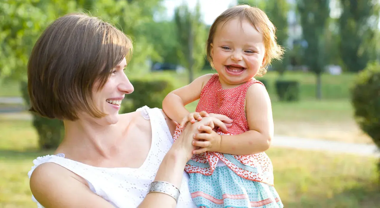 Mutter hält ihr lachendes Baby, das wie ein **baby sprung** vor Freude aussieht.
