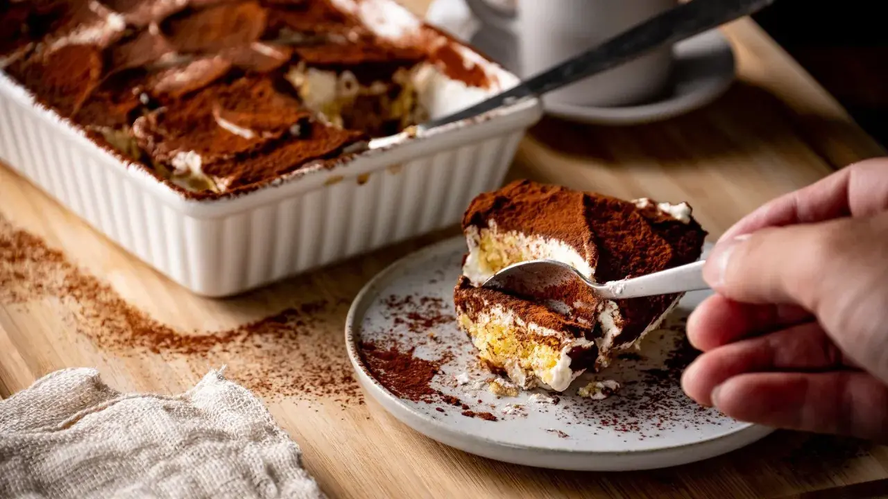 Ein Stück Tiramisu wird mit einer Gabel aus einer Auflaufform genommen. Perfekt für die Stillzeit!