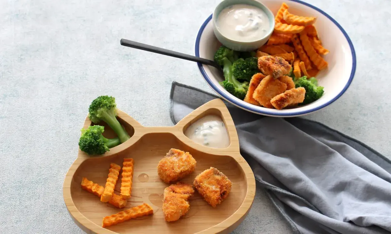 Fischstäbchen mit Brokkoli und Süßkartoffel-Pommes auf einem Katzen-Teller. Ab wann Fisch Baby essen darf, ist eine Frage für Eltern.