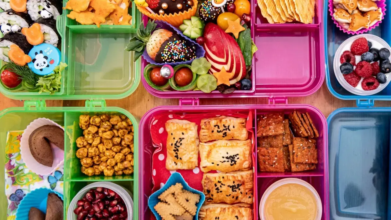 Bunte Bento-Boxen voller leckerer Snacks für die Autofahrt: Sushi, Obst, Kekse und Gebäck.