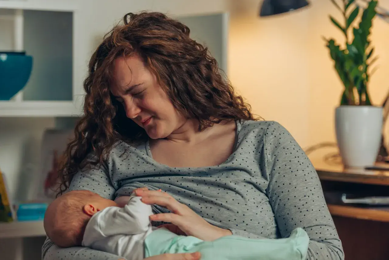 Mutter mit rissigen Brustwarzen stillt ihr Baby liebevoll, trotz des Schmerzes.