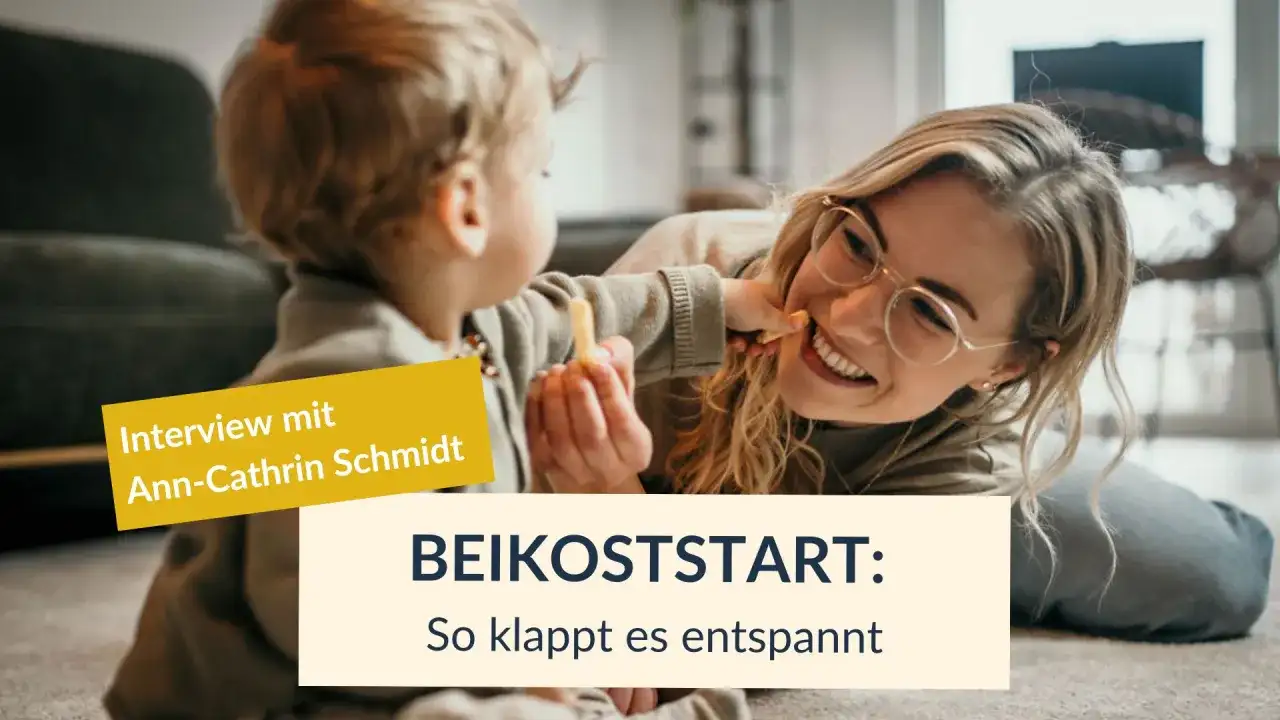 Ein lächelndes Baby mit BLW-Beikost-Snack im Mund, das seiner Mutter einen Snack anbietet.